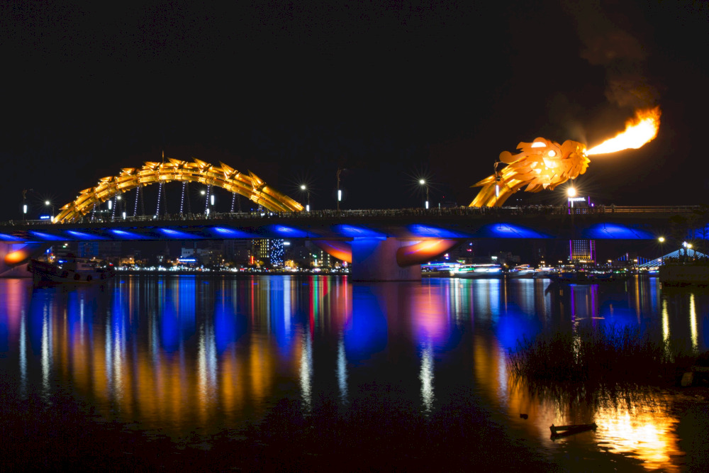 The Dragon Bridge in Da Nang, Vietnam, lights up the night as its golden dragon breathes fire, creating a mesmerizing spectacle over the Han River